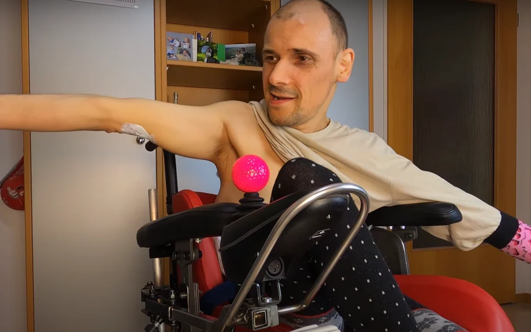 Video-Ausschnitt, bei dem er mit weit ausgestreckten armen im Rollstuhl sitzt
