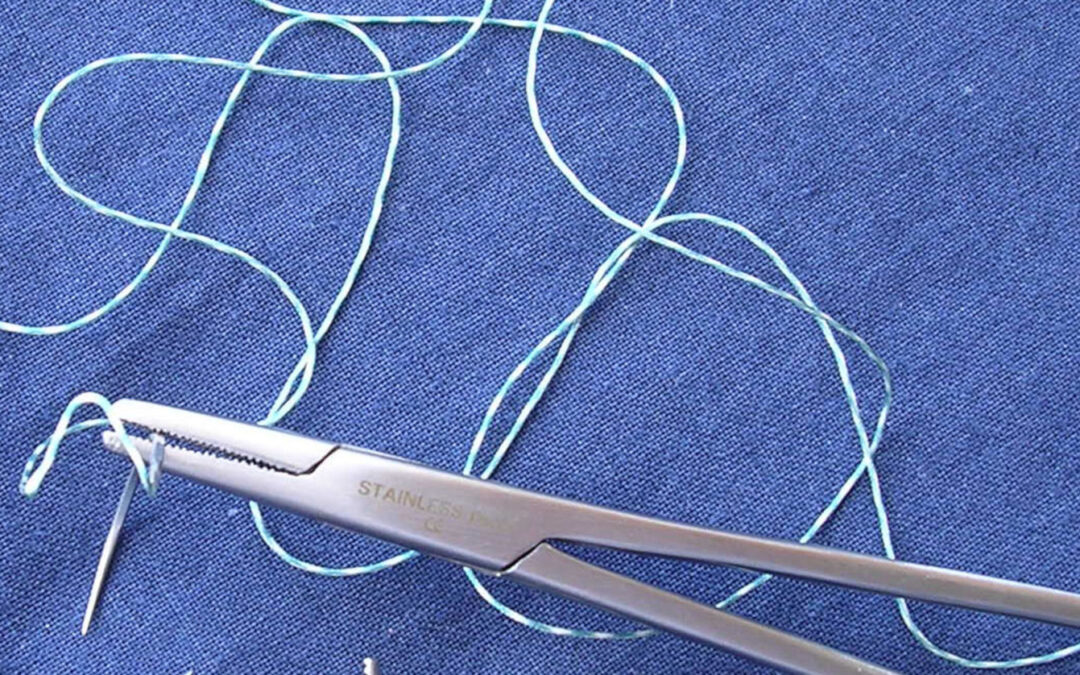 Nadel und Faden sowie Nadelhalter auf blauem Tuch