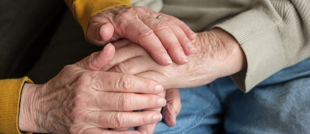 Hände von älterem Mann und älterer Frau halten sich gegenseitig.
