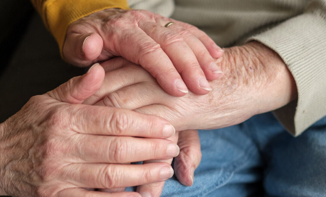 Hände von älterem Mann und älterer Frau halten sich gegenseitig.