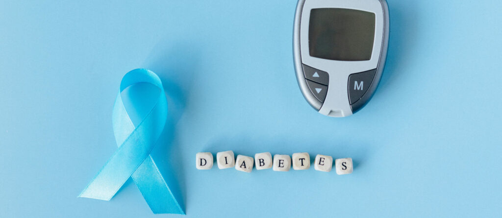 Schriftzug "Diabetes", Messgerät und hellblaue Awareness-Schleife