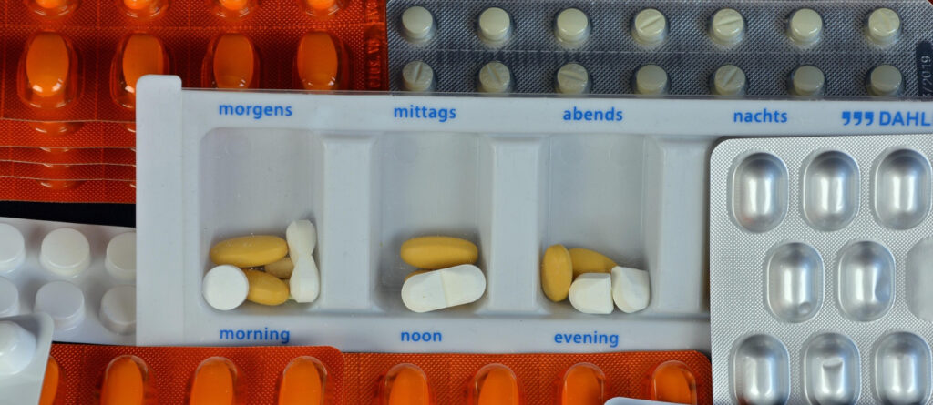 Tablettenbox und viele Blister mit verschiedenen Tabletten.