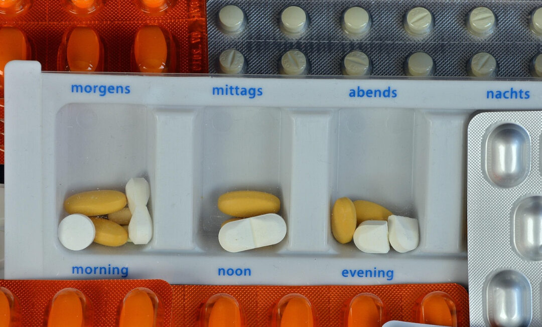 Tablettenbox und viele Blister mit verschiedenen Tabletten.