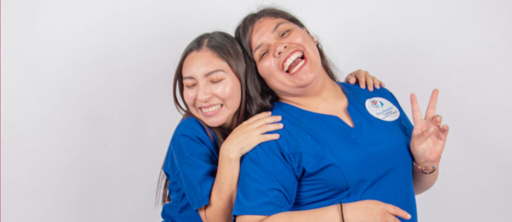 2 Pflegekräfte, die sich lachend in den Armen liegen.