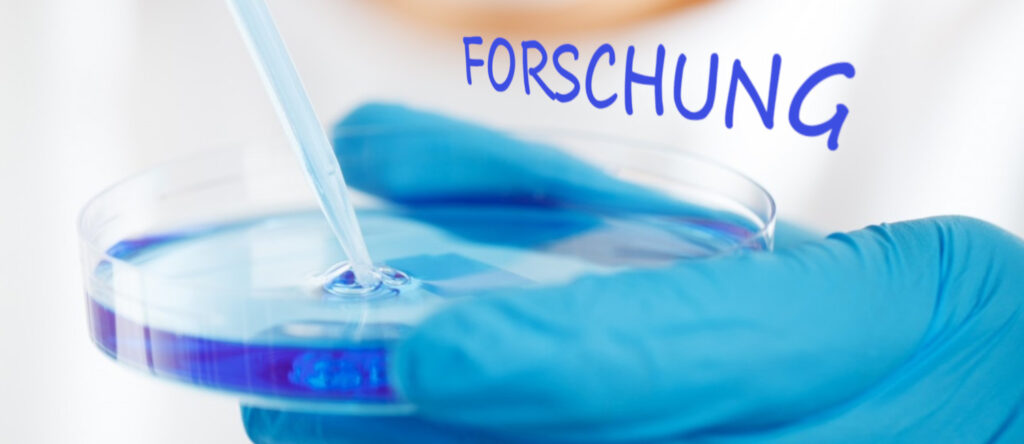 Eine behandschuhte Hand hält eine Petrischale mit Flüssigkeit, in die gerade eine Pipette gesenkt wird.